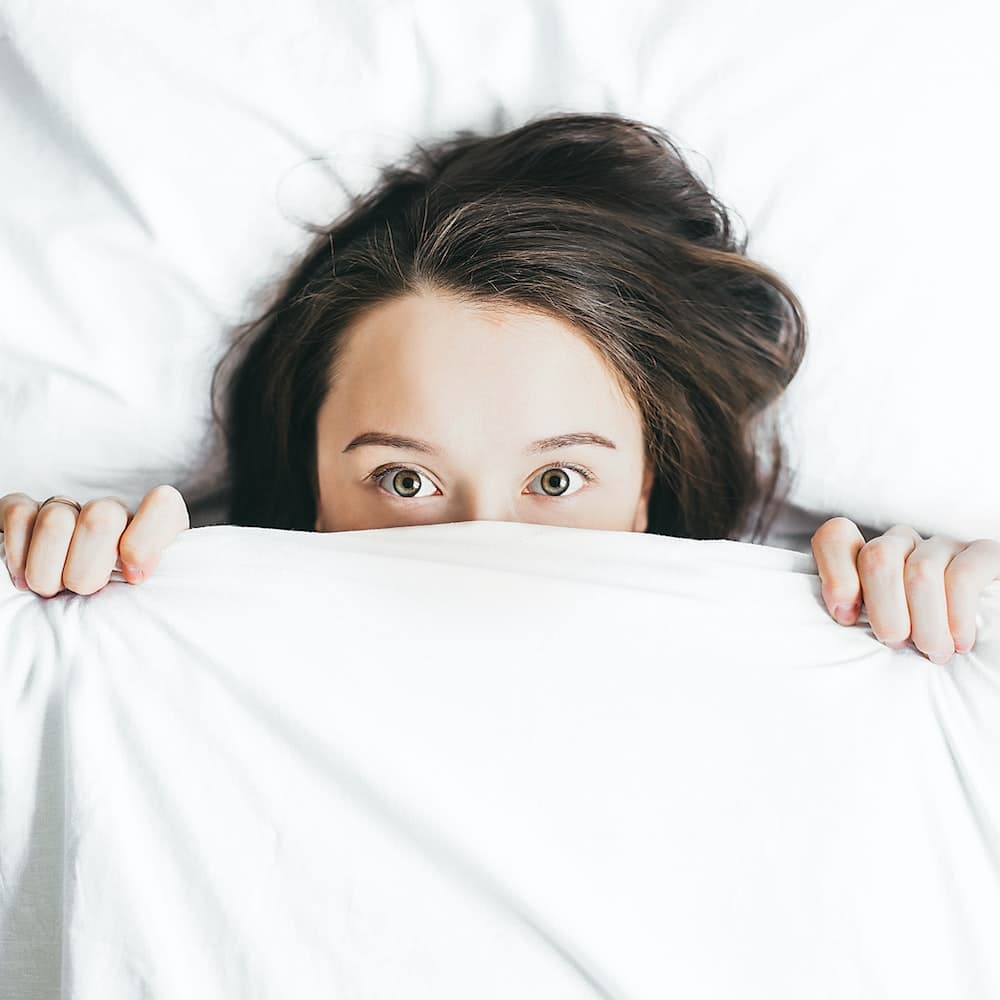 Woman covering her face with blanket